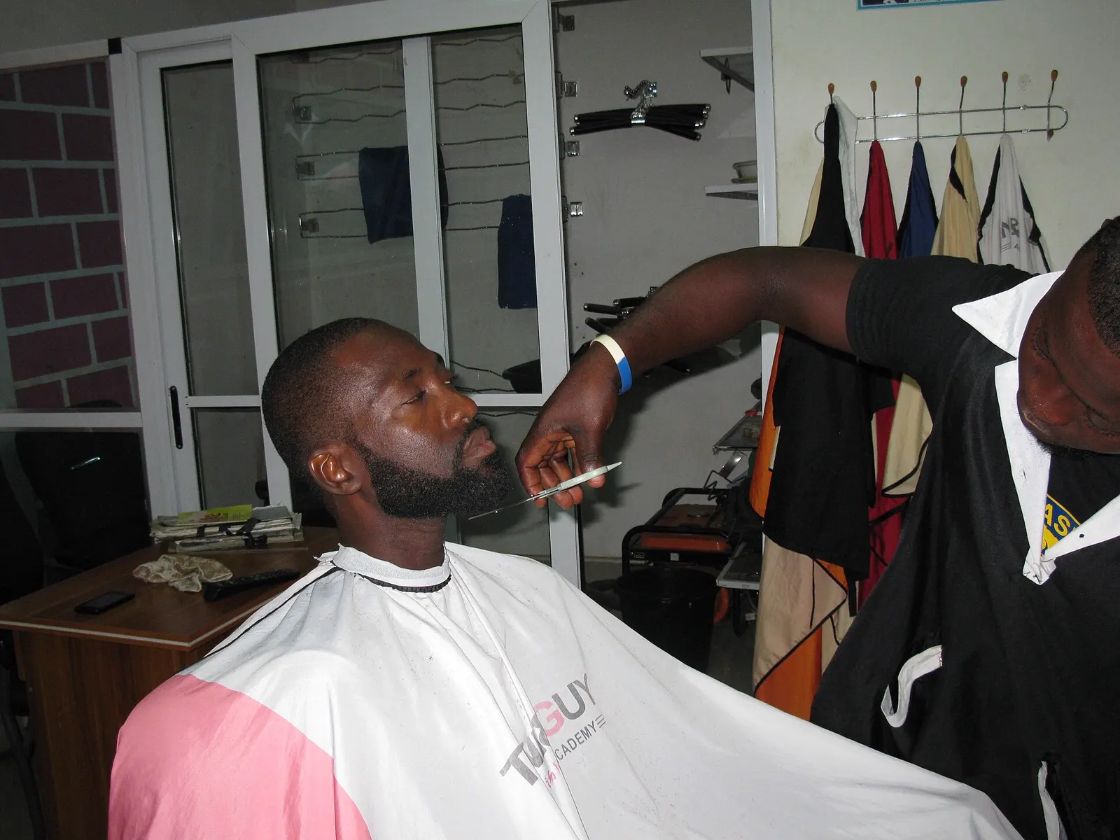Barbeiro aparando a barba de um cliente